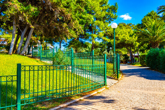Well kept walkway in park with green fence Voula Greece.