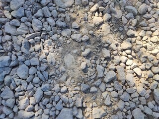 Close-up of rough gravel surface showcasing various stone sizes and textures under natural light for potential outdoor design use