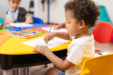 Close-up of a Latin boy in kindergarten coloring a recycling-themed assignment