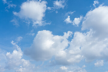 Beautiful fluffy white clouds drift across a bright blue summer sky