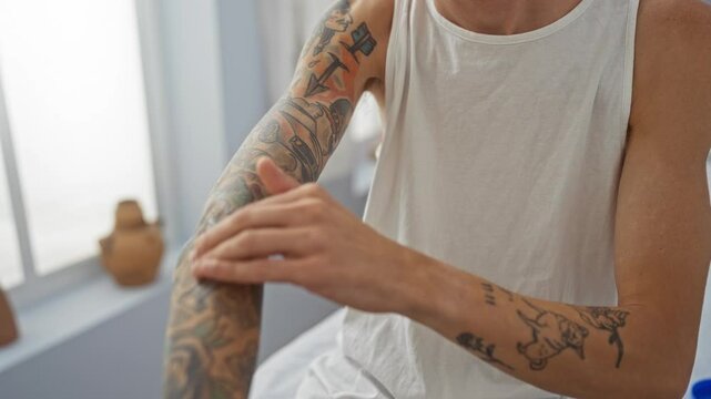 Young man with tattoos applying cream on his arm in a spa salon, emphasizing his relaxed demeanor and the wellness ambiance of the room.