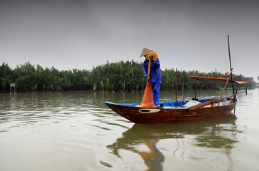 Obraz premium Fisherman in a canal of the Seven-acre coconut forest in Hoi An, Vietnam