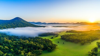 Fototapeta premium A breathtaking morning landscape featuring rolling green hills, misty valleys, and a vibrant sunrise illuminating the scene.