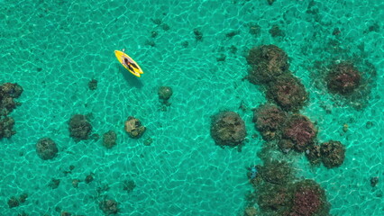 Young woman gracefully kayaks through crystal-clear turquoise waters in a tropical paradise, under...