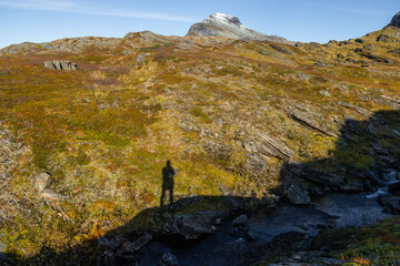 Beautiful sunny autumn scenery with hiker shadows on the mountain slope in Northern Norway. Seasonal scenery of Scandinavia.