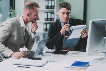 Fototapeta premium Two businessmen working together Analyze financial reports with charts and graphs while using the calculator to calculate budget, income, taxes, business growth. Startup business idea.