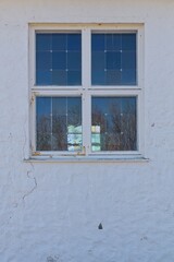 Fototapeta premium Glass window with white frame on stone wall.