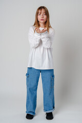 Young woman in white long-sleeve shirt blowing a kiss against a plain background