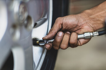 The auto mechanic is checking the tires and inflating the wheels.