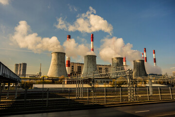 Smoking pipes of power plants against the blue sky. Puffs of steam over cooling towers.