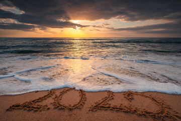 Sunrise Over Ocean Waves and Beach with 2025 text Written in Sea Sand, concept for travel, vacation, nature and relax
