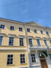 Obraz premium large yellow building with multiple windows and an arched doorway, showcasing classical architectural design. The structure reflects the enduring appeal of historical elegance in urban environments.