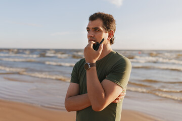 45 year old man standing with walkie-talkie on a beach by sea
