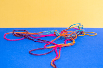 Yellow and blue paper background with colourful wool, concept fabric, crafting, knitting, hobby. Copy space.
