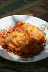 A plate of fried banana or Pisang Goreng (Musa acuminata × balbisiana), an Indonesian favorite snack. Sliced kepok bananas coated in batter and fried until crispy, offering a sweet, delightful taste.