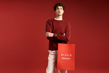 A trendy young man showcases his stylish look while holding shopping bags during Black Friday in a...