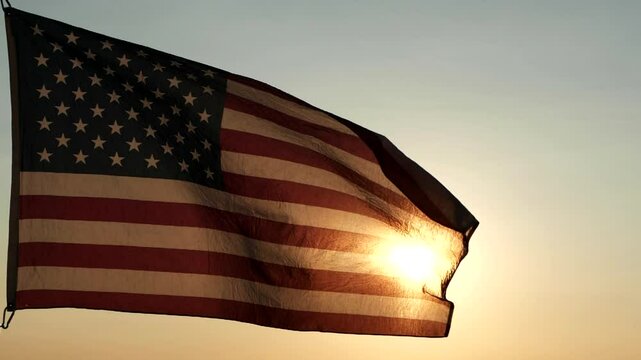 Veterans Day, Memorial Day. Silhouettes of American flag waving in the sky against sunset or sunrise background. Concept of US Holidays 4th of July, Independence Day, Veterans Day, Celebration, Labor
