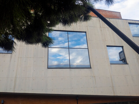 Reflejo del cielo en una ventana de un muro de hormig&oacute;n