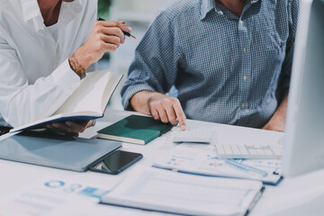 Two businessmen working together Analyze financial reports with charts and graphs while using the...