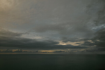 Raining sunset sky over the Atlantic Ocean, Tenerife. Minimalism. Misty dusk in the sea. Dramatic view. Tranquil empty landscape with soft golden gray sky. Natural gloomy weather.
