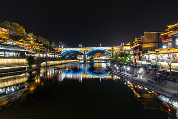 Obraz premium Chinese tourist attraction destination - Feng Huang Ancient Town (Phoenix Ancient Town) on Tuo Jiang River illuminated at night. Hunan Province, China