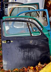 Stack of old, rusted car doors piled together in an outdoor setting