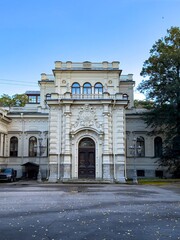 Obraz premium A frontal view of an elegant neoclassical building showcasing intricate architectural details. The building features a grand arched entrance adorned with decorative sculptures, ornate moldings, and
