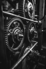 Close up of a machine with many gears. Concept of complexity and intricacy, as the gears are interlocked and interdependent. The black and white color scheme adds to the overall mood of the image