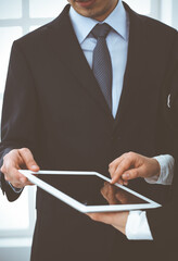 Businessman and woman using tablet computer for discussing questions in office. Partners or colleagues at meeting. Business cooperation concept