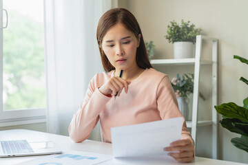 Deduction planning, debt asian young woman  hand using calculator to calculating money balance from bill and income, cost budget expenses for pay money form personal individual on table at home.