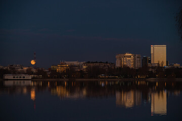 The lake in the Herastrau park at dusk. Night landscape with Skyscrapers with lit lights reflecting in the water at night