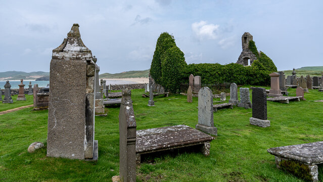 Blick auf die Kirche von Balnakeil inmitten des Friedhofs, im Hintergrund erkennt man den Balnakeil Strand unter blauem Himmel