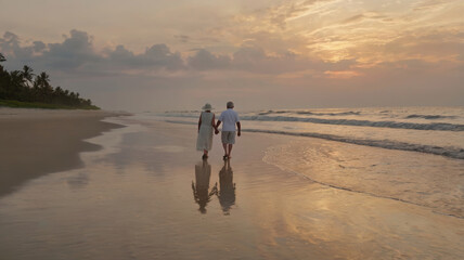 elderly couple walking at the beach