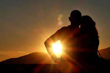 couple en contre-jour avec soleil se couchant dans le bras de l'homme