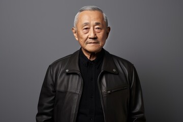 Obraz premium Portrait of a tender asian elderly man in his 90s sporting a classic leather jacket in minimalist or empty room background