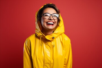 Fototapeta premium Portrait of a grinning woman in her 30s wearing a vibrant raincoat isolated on solid color backdrop