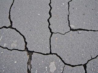Obraz premium Close-up of rugged textured asphalt surface with cracks and debris, old, gritty