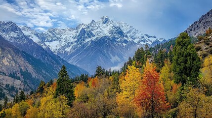 Majestic snow-capped mountain peak rising above a valley of vibrant fall foliage.