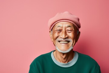 Portrait of a smiling asian man in his 70s sporting a trendy beanie in solid pastel color wall