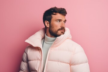 Obraz premium Portrait of a tender man in his 20s donning a durable down jacket in front of solid pastel color wall