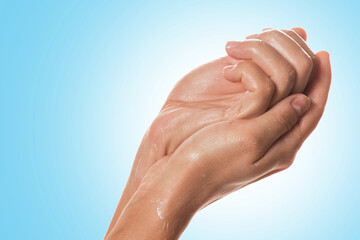 Fototapeta premium Hands applying moisturizing lotion on blue background.
