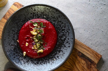 color photo of food, vegetarian food, beetroot and chickpea hummus, cashew nuts, celery, dark rustic plate, close-up view