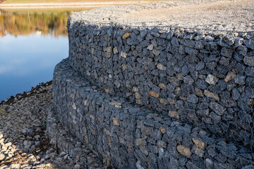 A large pile of rocks positioned beside a serene body of water, creating a beautiful natural...