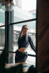 Fashion portrait of an informal girl with dreadlocks and piercings in a gray top behind the bar in...