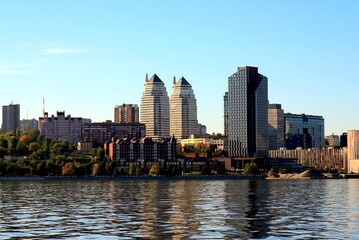 Naklejka premium Big city on banks wide river. Ukrainian city Dnipro, Ukraine. Beautiful modern towers, buildings, skyscrapers, water morning, Dnepr