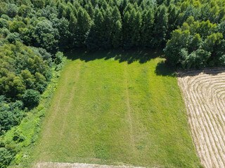 Aerial view of a lush green field bordered by dense woods, showcasing the beauty of nature and...