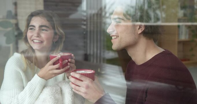 Christmas time, Couple enjoying hot cocoa together, gazing out window at home