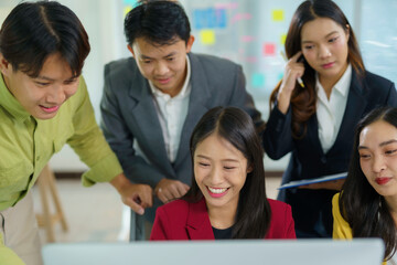 Fototapeta premium Asian businesspeople collaborating on a project, looking at computer screen and smiling, teamwork and success in modern office
