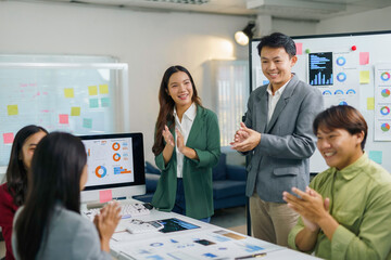 Asian businesspeople clapping hands during a presentation in a meeting room, celebrating successful...