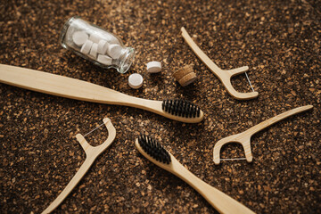 Bamboo Toothbrush, Floss Picks and Toothpaste Tablets on Cork Surface